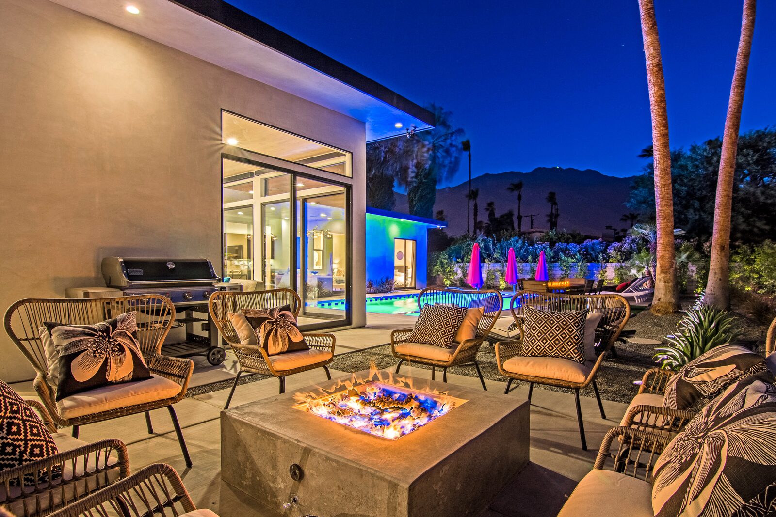5 Palms Estate outdoor fire pit with grill and lit pool beyond